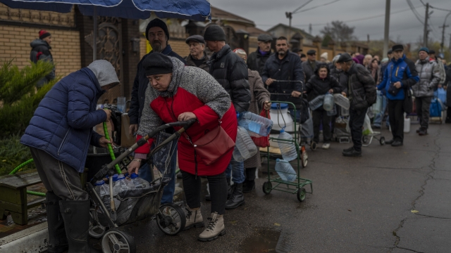 Ukrainians queue to fill containers with drinking water.