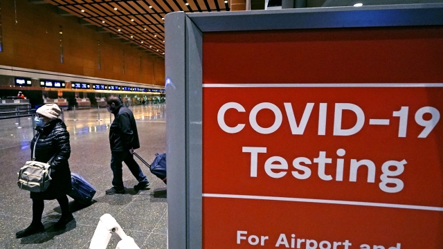 Travelers pass a sign near a COVID-19 testing site at Logan Airport.