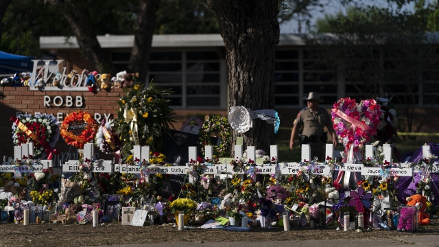Flowers and candles are placed around crosses at a memorial outside Robb Elementary School.