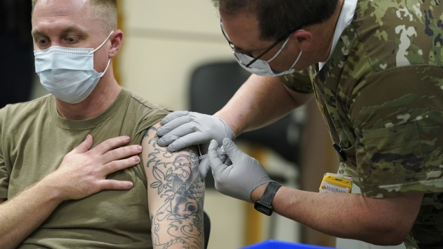 Staff Sgt. Travis Snyder, left, receives the first dose of the Pfizer COVID-19 vaccine.