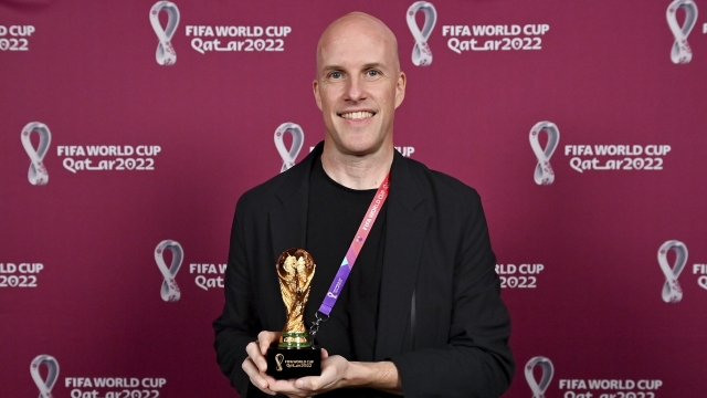 Grant Wahl smiles as he holds a World Cup replica trophy.
