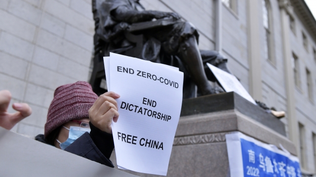 A demonstrator holds a paper saying, "End zero-COVID. End dictatorship. Free China."