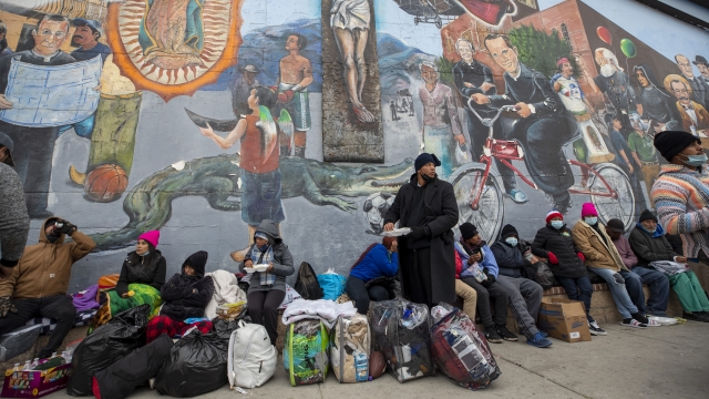 Migrants eat and wait for help while camping on a street in downtown El Paso, Texas.