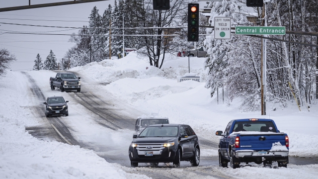 Cars drive on a snowy intersection.