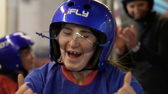 A child with special needs wears a helmet for indoor skydiving