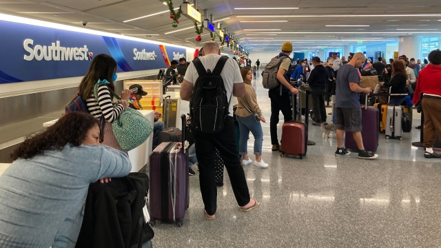 Southwest Airlines travelers wait to retrieve their bags after canceled flights.