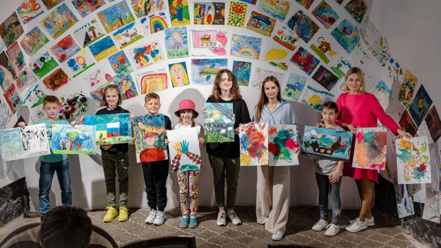 Nataliia Pavliuk, right, and her daughter Yustyna, third from right, st.and with children and their artwork
