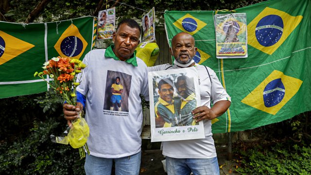 Two men in Brazil hold memorabilia honoring Brazilian soccer star Pele.
