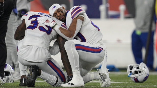 Buffalo Bills' teammates console each other after a teammate collapses during a football game.