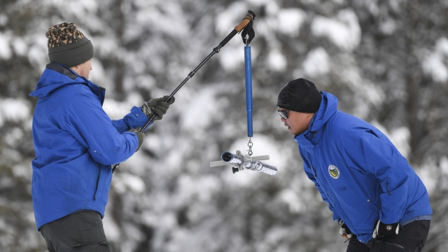 Two men work the measurement phase of the first media snow survey of the season.