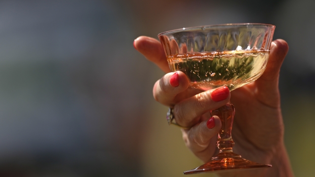 A woman holds a glass of sparkling wine