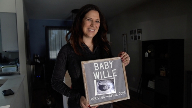 Kelly Willie poses with an ultrasound photo of her child, due April 2023