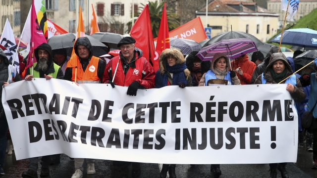 Demonstrators from unions hold a banner reading in French "Withdrawal of this unfair pension reform" during a demonstration.