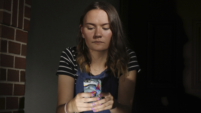 Rachel Whalen looks at her phone at her home in Draper, Utah.