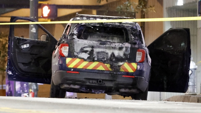 A burned police car sits on the street following a violent protest.
