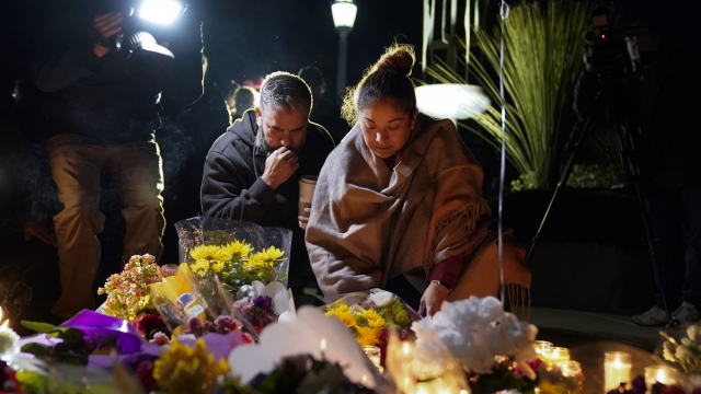 A couple pauses at a memorial at a vigil honoring the victims of a shooting at Star Ballroom Dance Studio