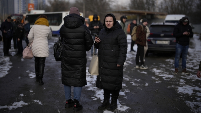 People wait on a street blocked by police after a rocket attack in Kyiv, Ukraine.