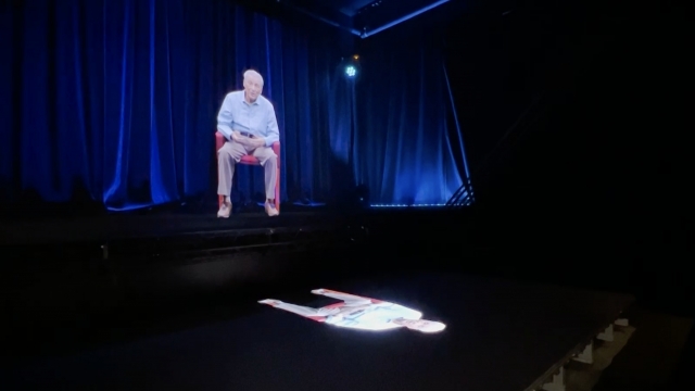 A hologram of Aaron Elster is shown.
