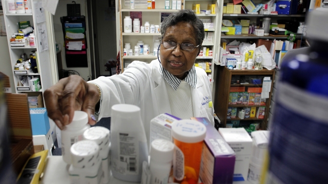 A doctor looks at a shelf of prescription drugs.