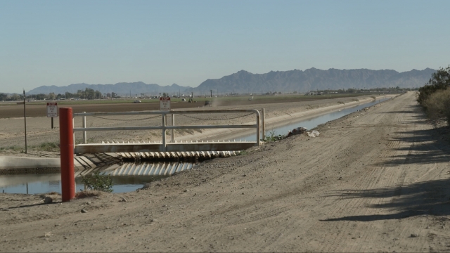 A dry irrigation canal runs between two unplanted fields.