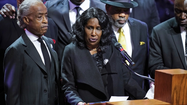 Flanked by Rev. Al Sharpton, left, and her husband Rodney Wells, RowVaughn Wells speaks
