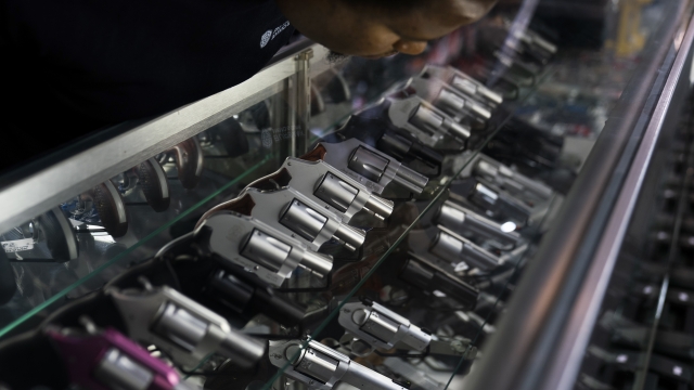 A sales associate arranges guns on display.