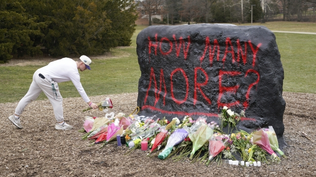 A student leaves flowers at The Rock on the grounds of Michigan State University