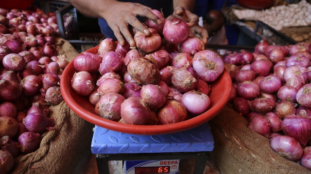 a vendor weighs onions for a customer at a farmers market in Bangalore, India
