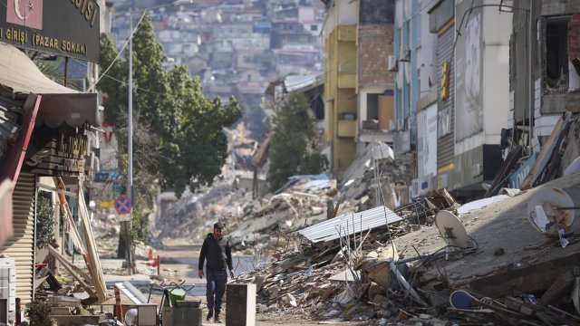 A man walks past destroyed buildings in Antakya, southeastern Turkey