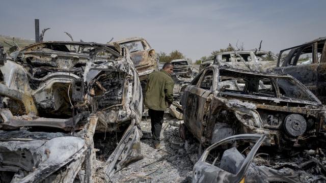 A Palestinian man walks between scorched cars in a scrapyard, in the town of Hawara, near the West Bank city of Nablus