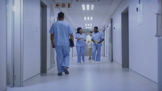 Nurses walk through a hospital hallway.