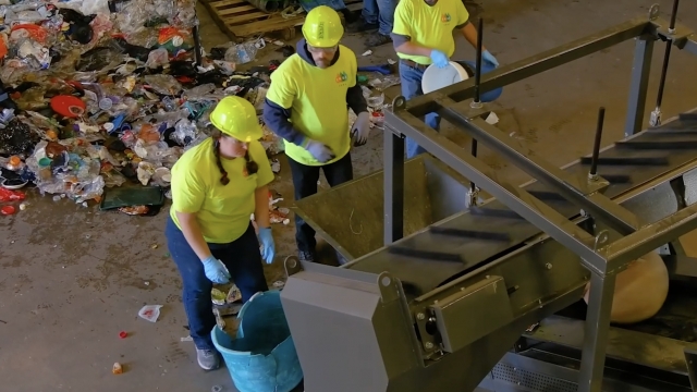 Workers put plastic into a factory machine.