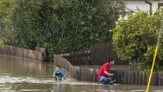 A boy and a man ride bicycles through floodwaters in Watsonville, California.