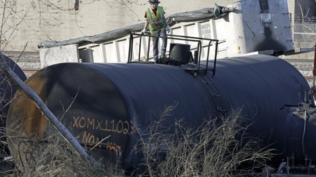 A worker stands on a derailed train car