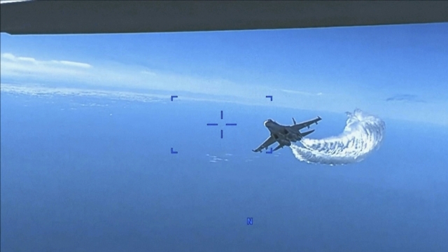 Russian Su-27 approaching the back of an MQ-9 drone and beginning to release fuel as it passes, over the Black Sea
