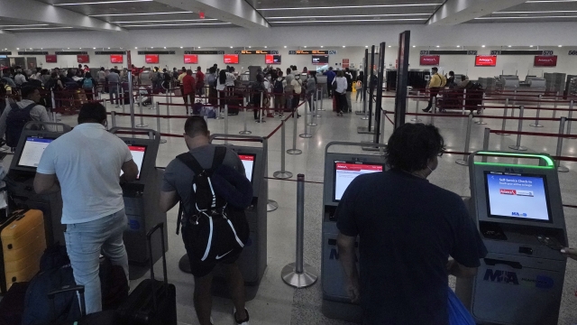 Travelers check in on kiosks at Miami International Airport, Friday, July 1, 2022, in Miami.