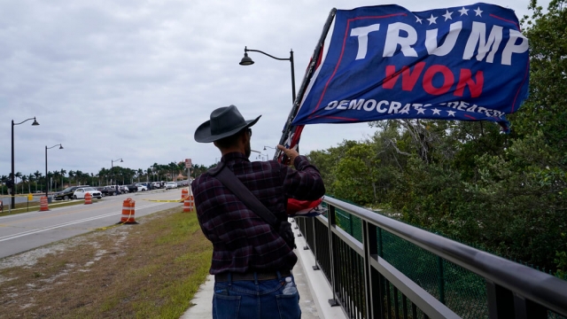 A supporter of former President Donald Trump walks across the bridge across from his Mar-a-Lago estate