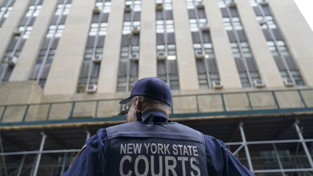 A New York State court officer stands guard outside the District Attorney's office