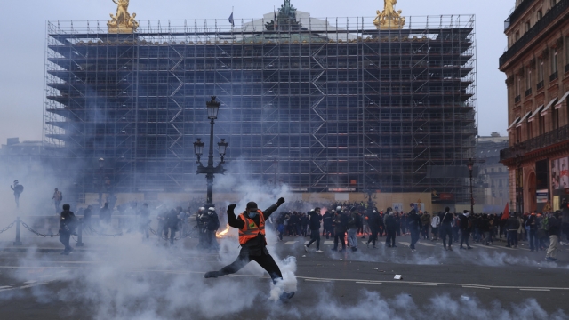 A protester kicks a tear gas canister in front of the Opera at the end of a rally in Paris