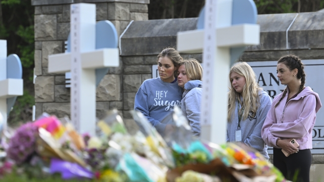 Students at a nearby school pay respects at a memorial for the people who were killed
