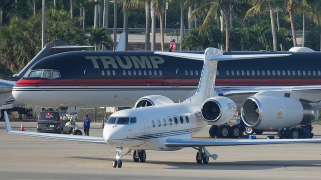 A small plane taxis past the private plane of former president Donald Trump as it sits parked at a Florida airport.