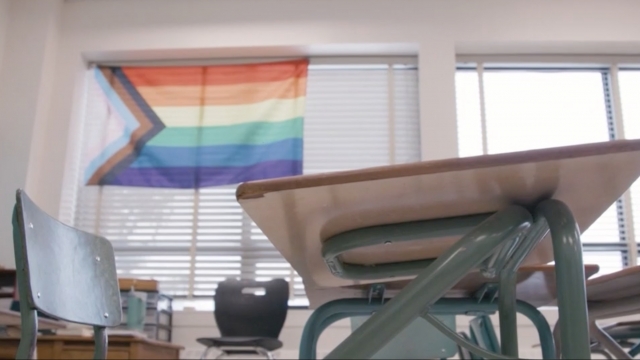 A rainbow flag hangs in a classroom.