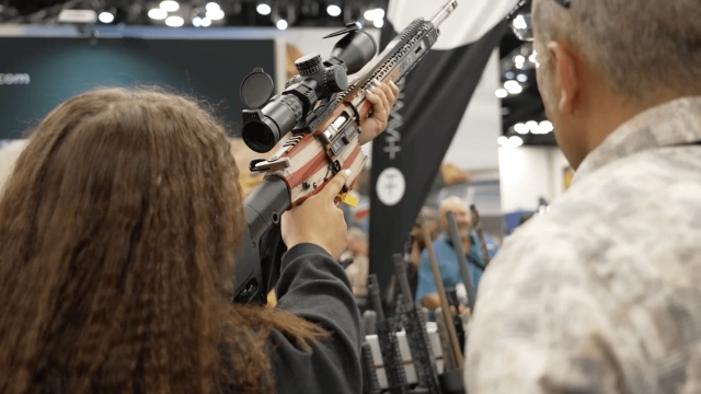 People holding guns at the NRA Convention.