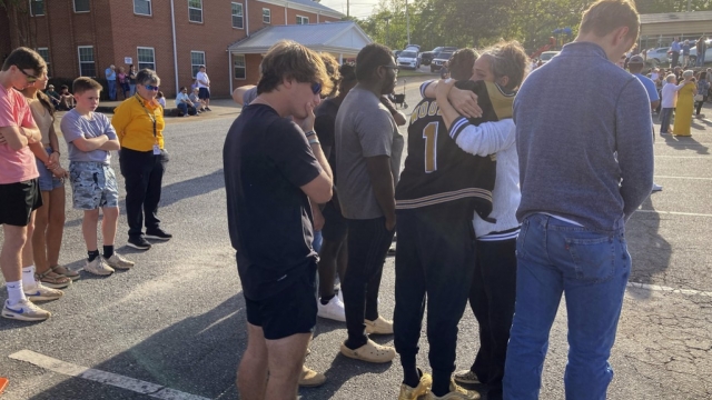 A woman embraces a Dadeville High School football player at a prayer vigil.