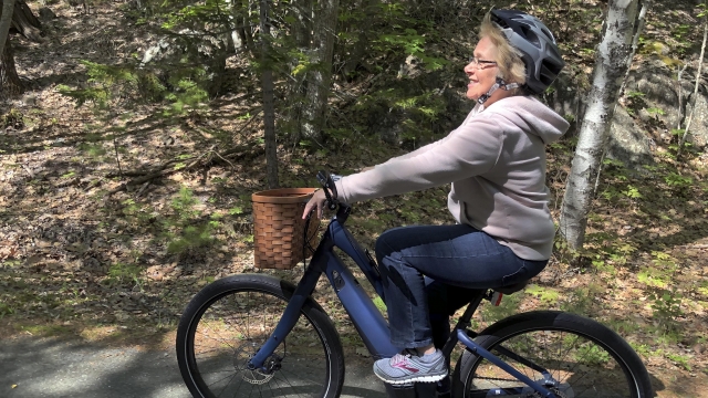 Janice Goodwin rides her electric-assist bicycle on a paved road in Acadia National Park.