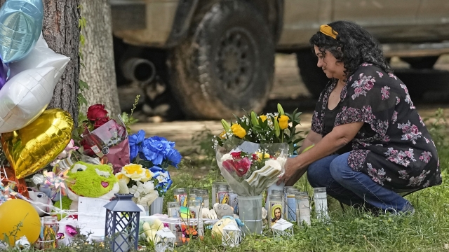 Maria Rodriguez places flowers outside the home where a mass shooting occurred Friday, in Cleveland, Texas