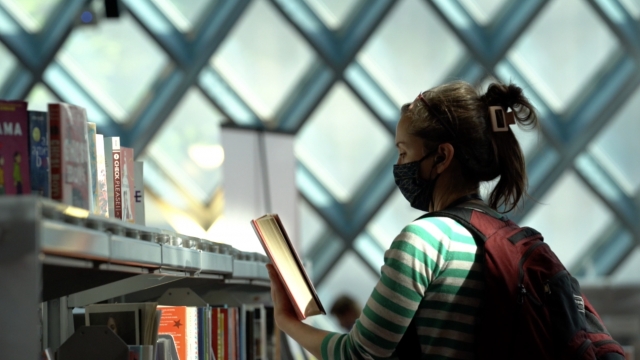 A woman picks up a book at a library