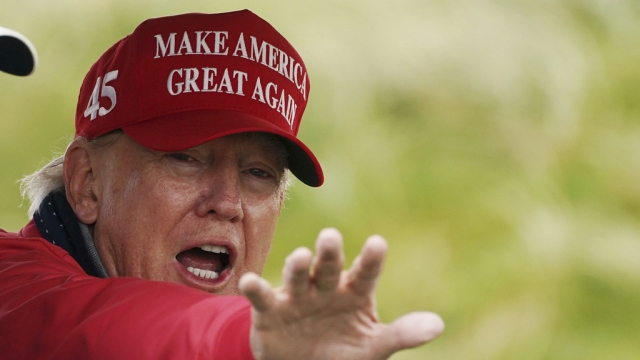 Former President Donald Trump gestures as he plays golf.