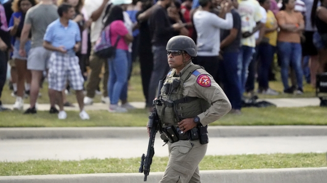 A law enforcement officer walks as people are evacuated from a shopping center where a shooting occurred.
