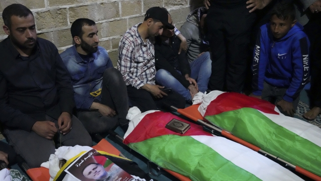 Mourners gather around bodies of Palestinians who were killed in Israeli airstrikes.